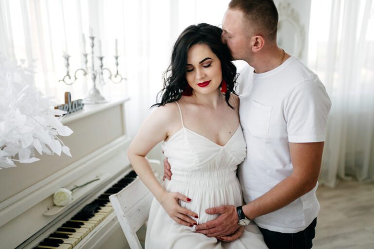 Maternity photography ideas - Couple of handsome husband and pretty pregnant woman posing at studio