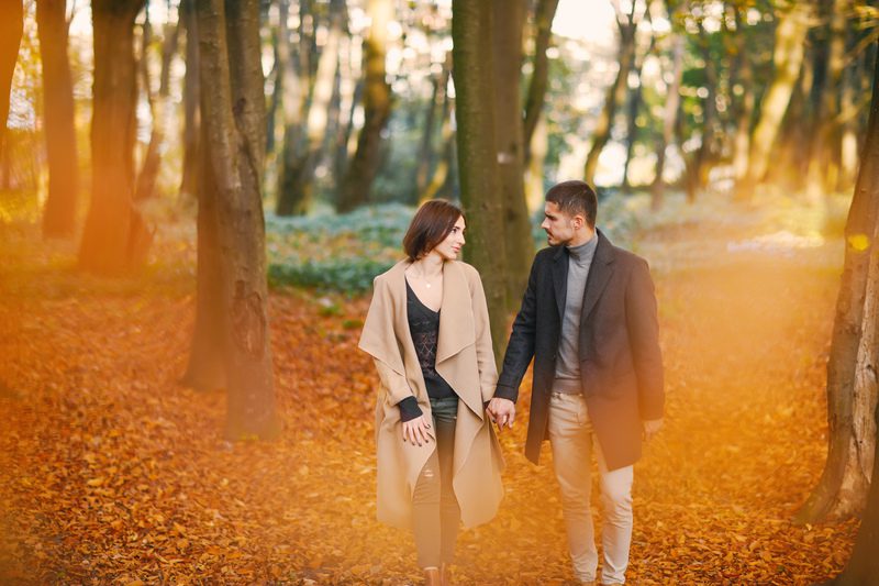 lovely couple walking around the park during autumn