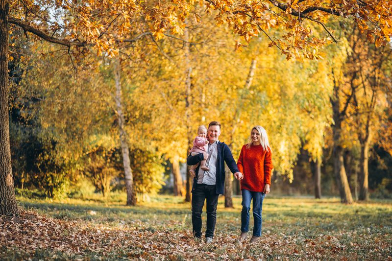 Family with baby daughter walking in an autumn park