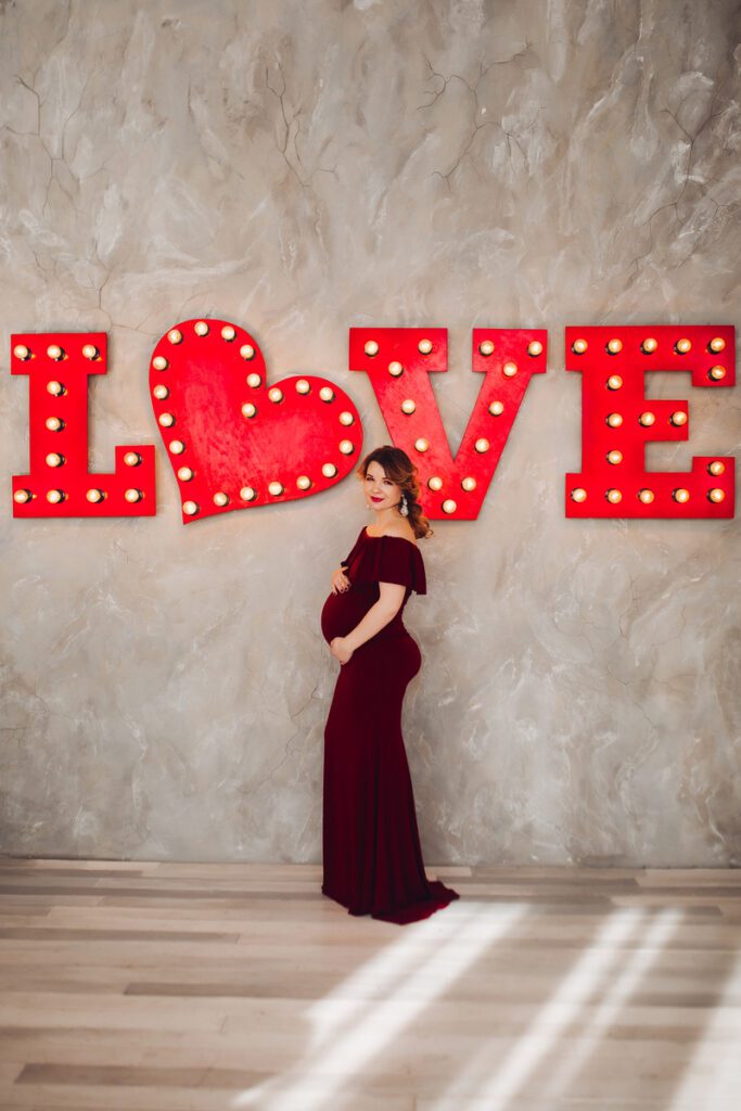 Maternity photography ideas - Charming pregnant woman in marsala dress posing on steps of house.