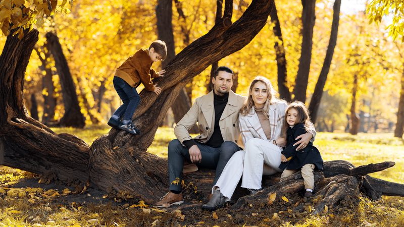 happy-family-autumn-park-mother-father-daughter-are-sitting-tree-trunk