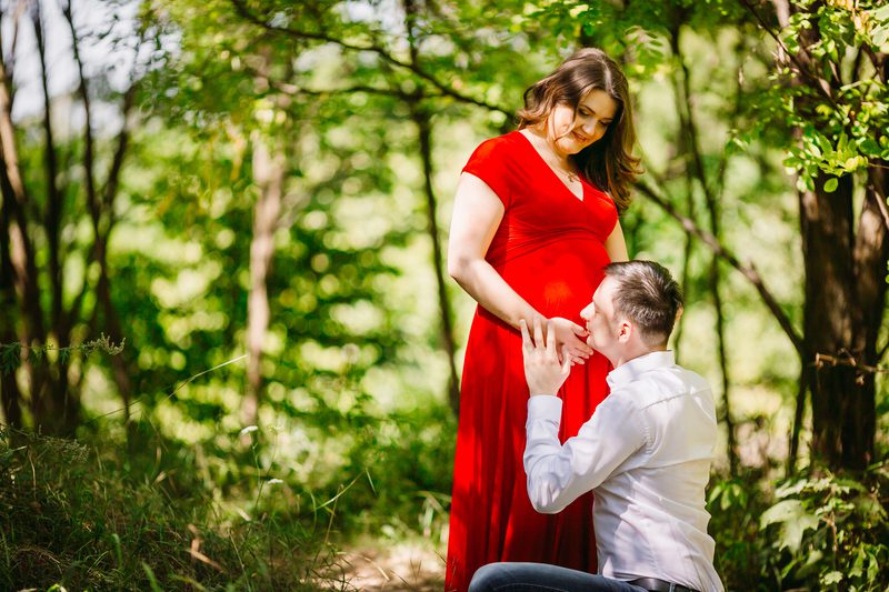 The husband with pregnant wife embracing in the forest