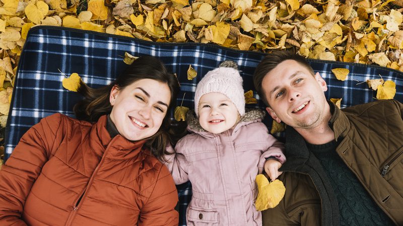 smiling-family-lying-autumn-park