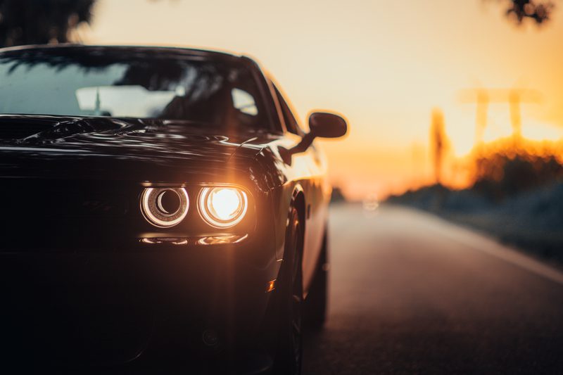 A luxurious car parked on the highway with an illuminated headlight at sunset Amazing-Car-Background-Images-For-Editing