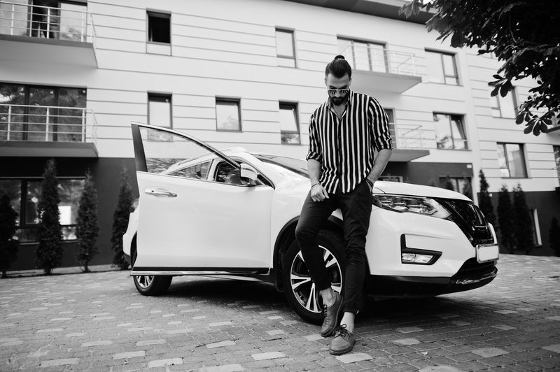 Successful man wear in striped shirt and sunglasses pose near his white suv car. Stylish men in transport.