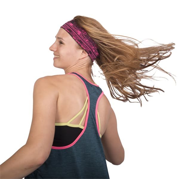 Woman with long hair wearing a patterned headband and activewear turning against a white background